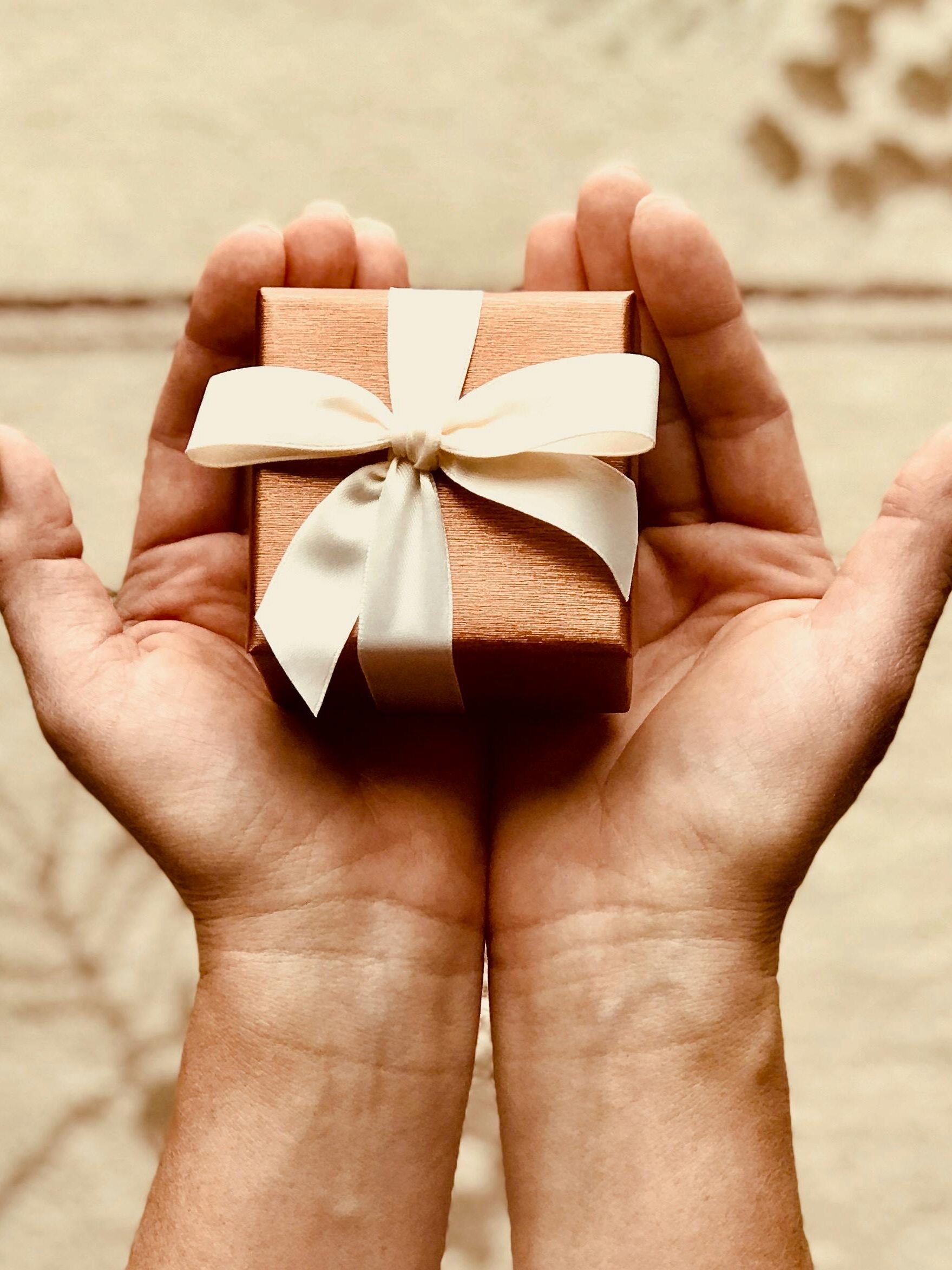 Close-up of hands holding a beautifully wrapped gift box with a ribbon, perfect for celebrations and surprises.